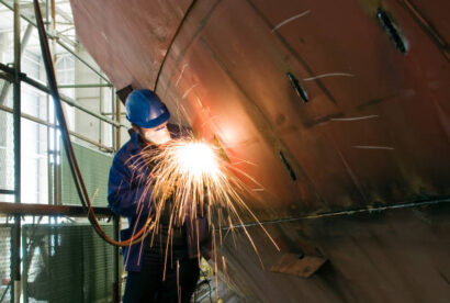 Welding new steel plates on a ship's hull during repair work on a ship in a dry dock.