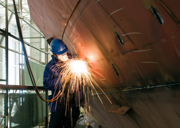 Welding new steel plates on a ship's hull during repair work on a ship in a dry dock.